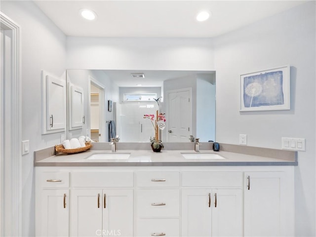 bathroom featuring double vanity, a shower stall, a sink, and recessed lighting