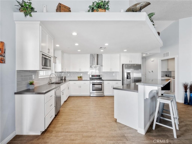 kitchen with a breakfast bar area, stainless steel appliances, visible vents, decorative backsplash, and wall chimney range hood