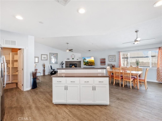 kitchen with visible vents, lofted ceiling, ceiling fan, open floor plan, and white cabinetry