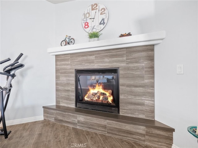 interior details with a fireplace, wood finished floors, and baseboards