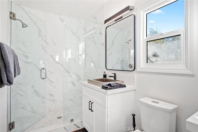 bathroom with toilet, a marble finish shower, and vanity