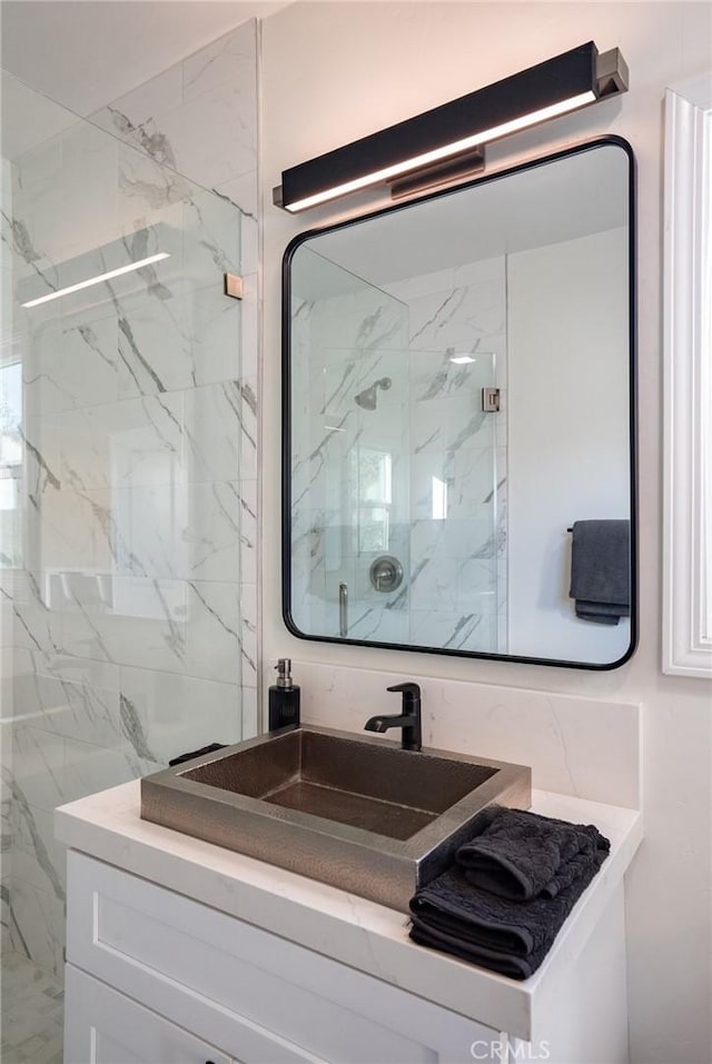 bathroom with vanity and a marble finish shower