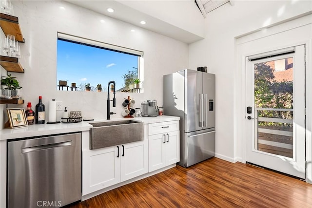 kitchen featuring appliances with stainless steel finishes, dark wood finished floors, light countertops, and a sink