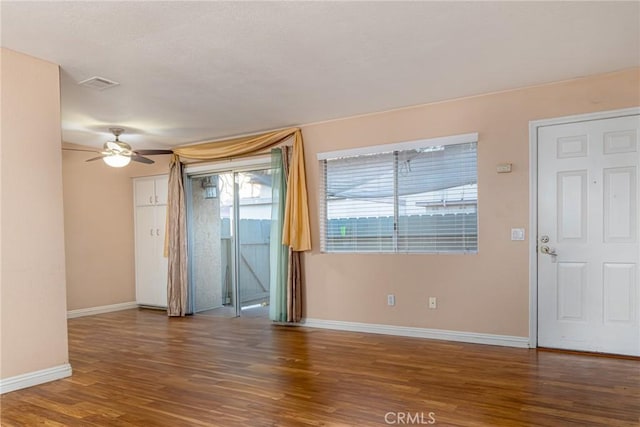 spare room featuring a ceiling fan, visible vents, baseboards, and wood finished floors