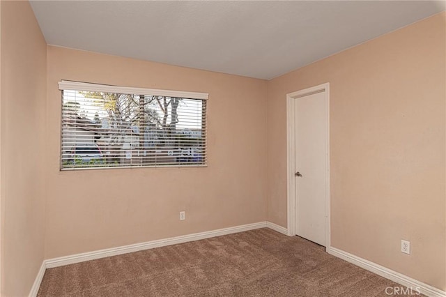 carpeted spare room featuring baseboards