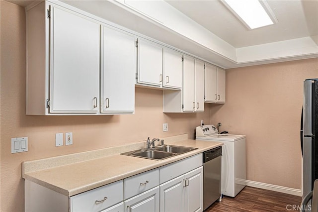 kitchen with stainless steel appliances, dark wood-style flooring, a sink, light countertops, and washer / clothes dryer