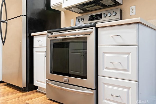 kitchen featuring light wood finished floors, appliances with stainless steel finishes, white cabinets, and light countertops