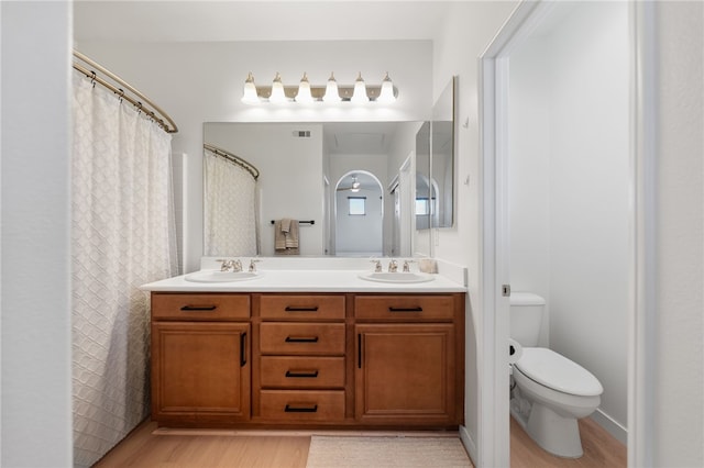 bathroom with a sink, toilet, double vanity, and wood finished floors