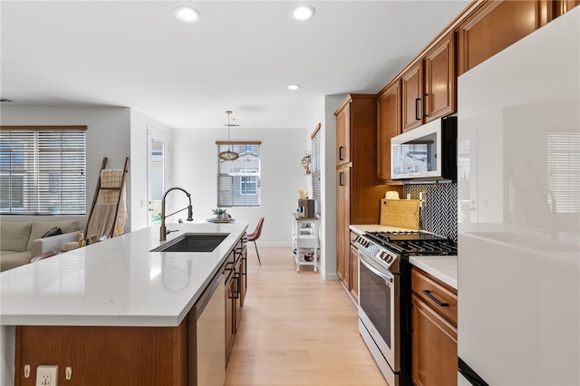 kitchen featuring light wood-style flooring, recessed lighting, appliances with stainless steel finishes, a sink, and brown cabinets
