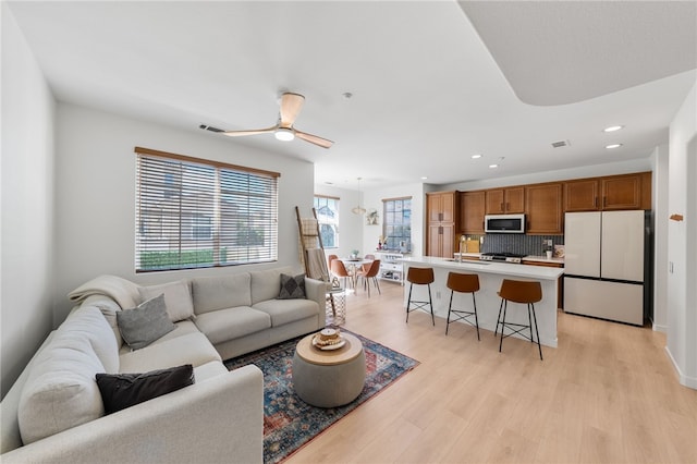 living area featuring light wood-style flooring, a ceiling fan, visible vents, and recessed lighting