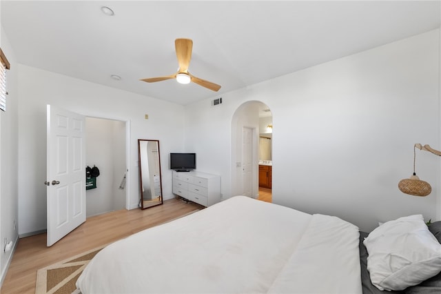 bedroom with arched walkways, ceiling fan, visible vents, and light wood-type flooring