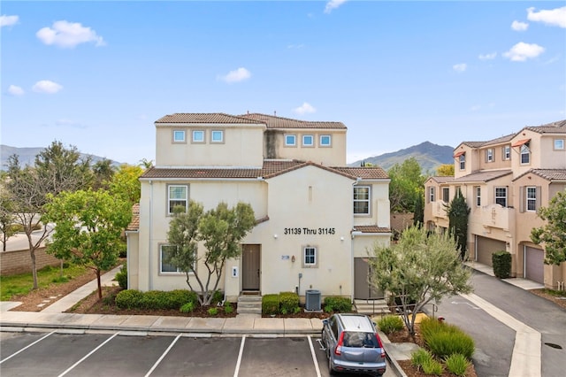 view of front of house featuring uncovered parking, a mountain view, stucco siding, and a tile roof