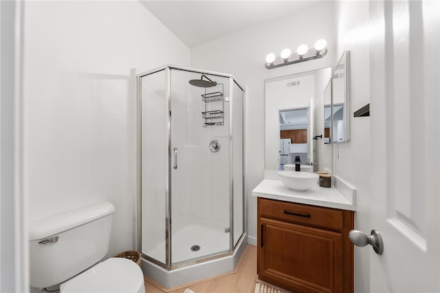 bathroom with visible vents, vanity, a shower stall, and toilet