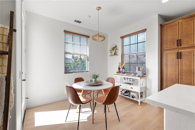 dining space with light wood-style flooring, plenty of natural light, visible vents, and baseboards