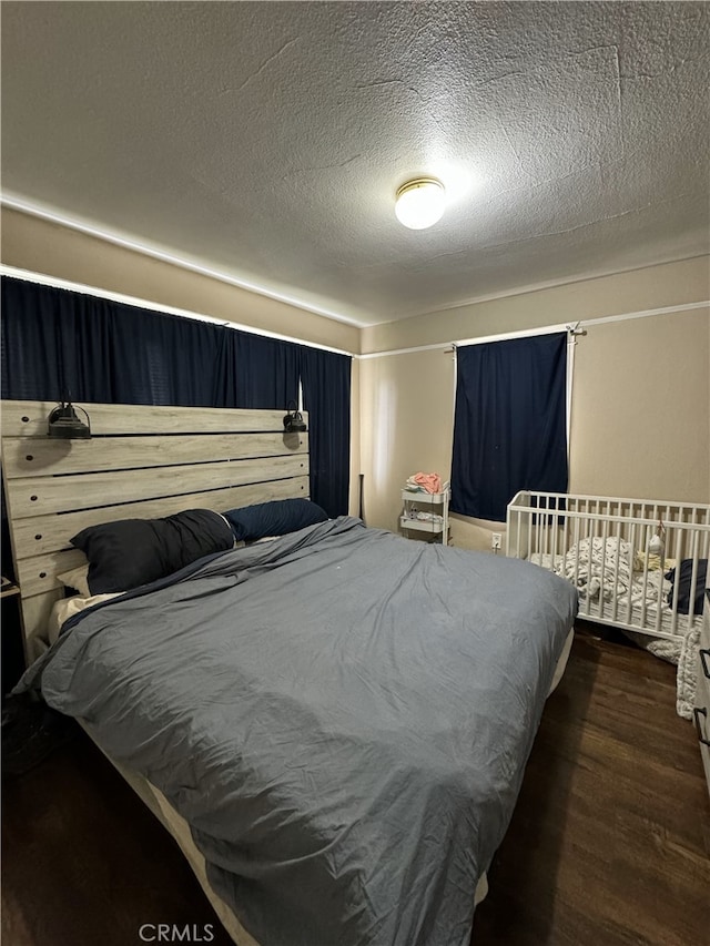 bedroom with a textured ceiling and wood finished floors