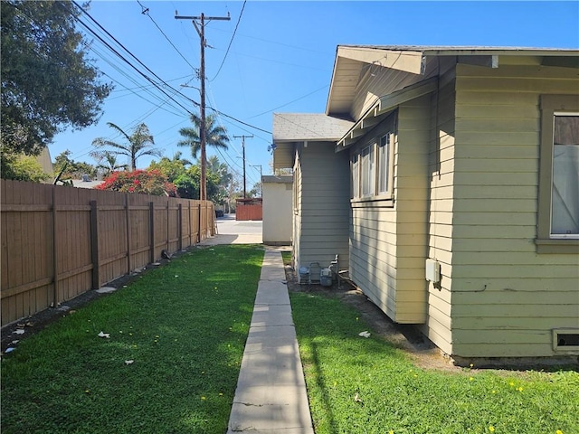 view of home's exterior with fence, a lawn, and roof with shingles