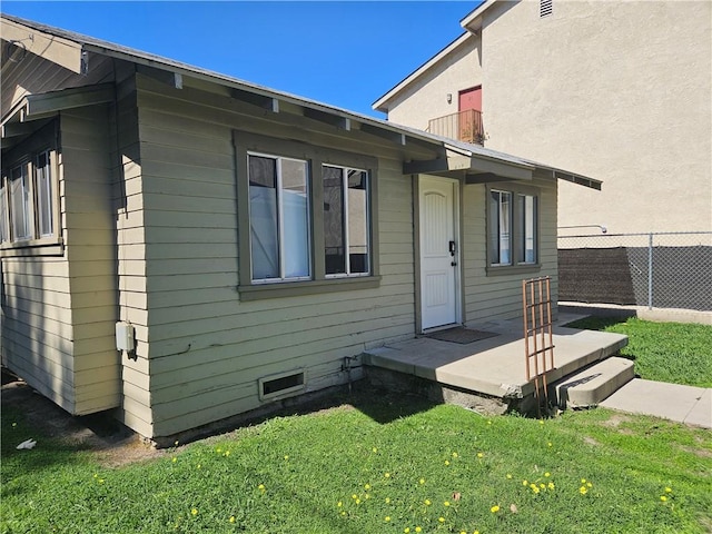 exterior space featuring a front lawn, crawl space, and fence