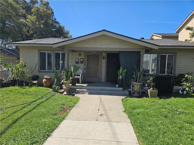 view of front of house with a porch, a front yard, and roof with shingles