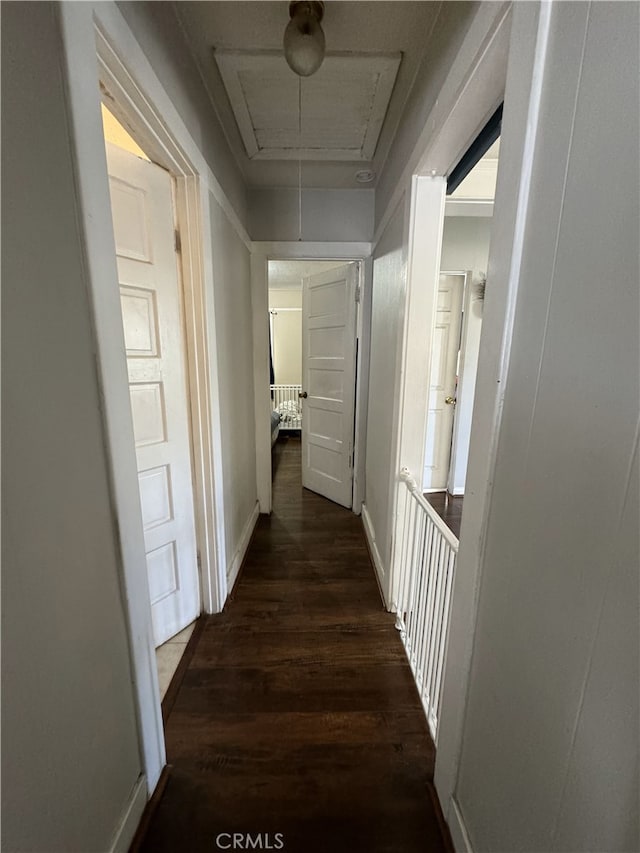 hall featuring attic access, baseboards, and wood finished floors