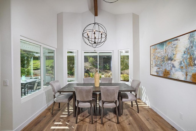 dining space with baseboards, beamed ceiling, wood finished floors, an inviting chandelier, and high vaulted ceiling