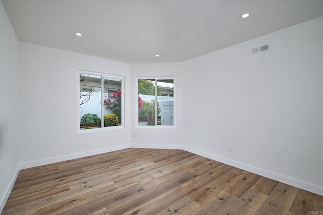 empty room featuring baseboards, visible vents, wood finished floors, and recessed lighting