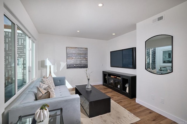 living room featuring baseboards, visible vents, wood finished floors, and recessed lighting