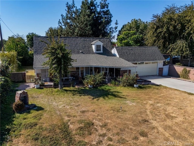 view of front of property featuring concrete driveway, an attached garage, fence, a porch, and a front yard