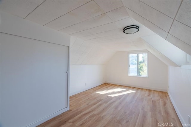 bonus room featuring light wood-type flooring, baseboards, and lofted ceiling