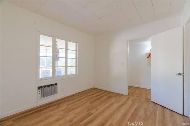 spare room featuring heating unit, light wood-style floors, and baseboards