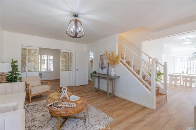 living area featuring wood finished floors, stairway, and an inviting chandelier