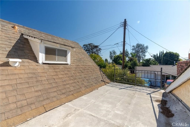 view of property exterior with a shingled roof and a patio area