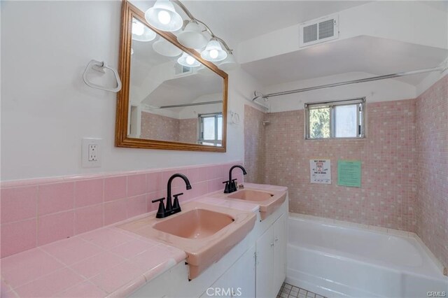 full bathroom featuring bathtub / shower combination, a sink, visible vents, and tile walls