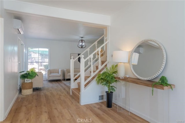 interior space with a wall mounted AC, wood finished floors, and baseboards