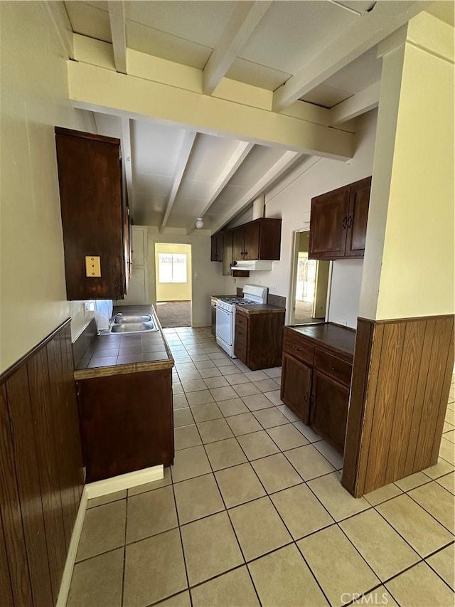 kitchen with wood walls, a wainscoted wall, white range with gas cooktop, and lofted ceiling with beams