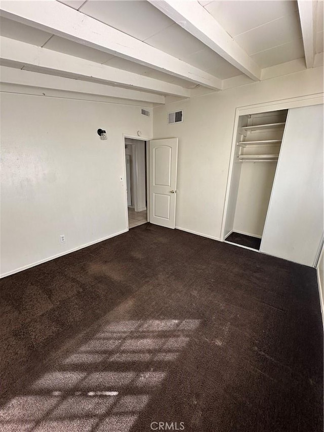 unfurnished bedroom featuring carpet floors, beam ceiling, visible vents, and baseboards