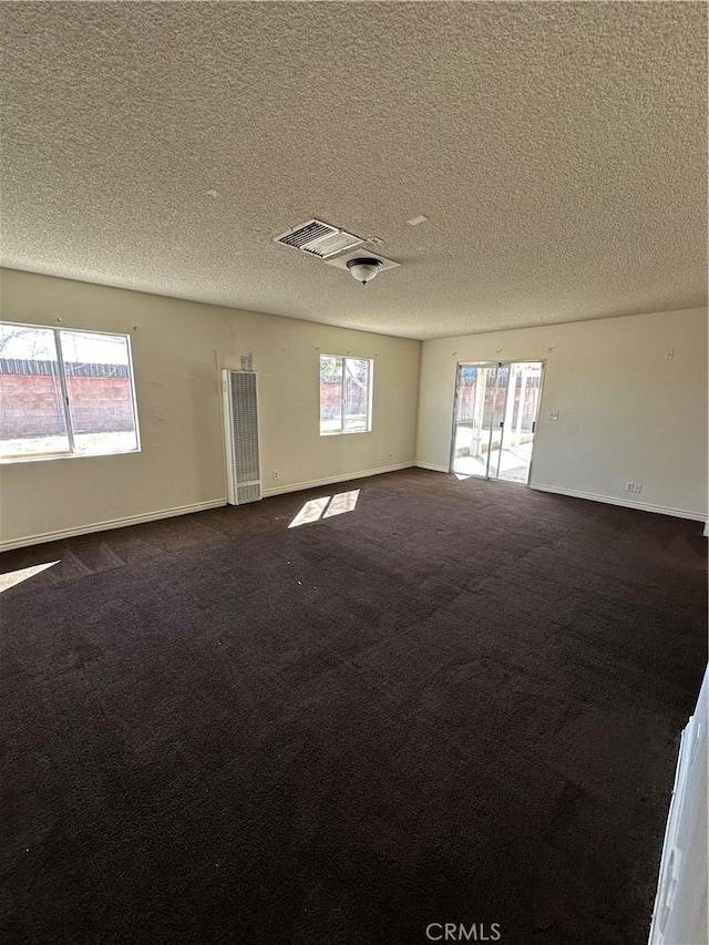 unfurnished room featuring dark carpet, a textured ceiling, and baseboards