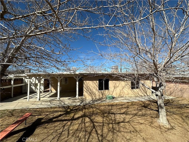 back of property featuring a patio area, a chimney, and stucco siding