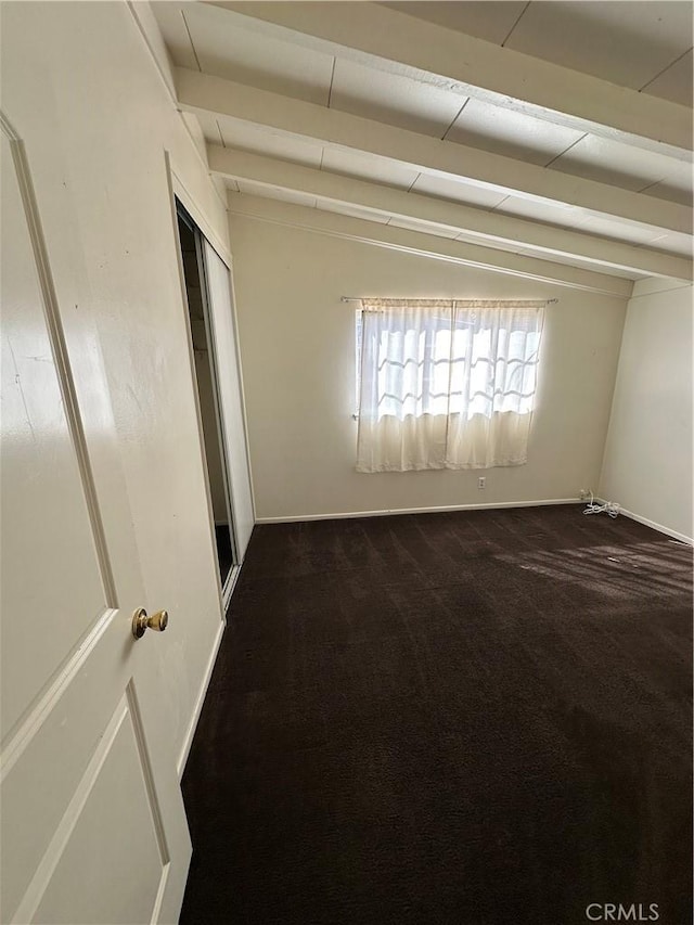 empty room with dark colored carpet and beam ceiling