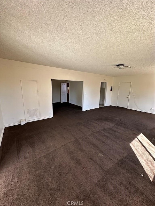 interior space featuring visible vents, dark colored carpet, and a textured ceiling