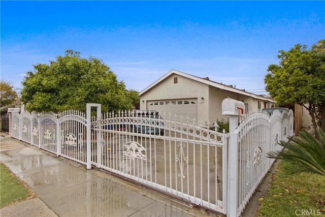 view of front of house with a gate, a garage, a fenced front yard, and stucco siding