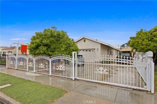 view of front of property with stucco siding, a garage, a fenced front yard, and a gate