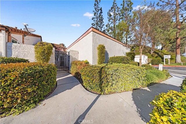 view of side of home featuring a gate and stucco siding