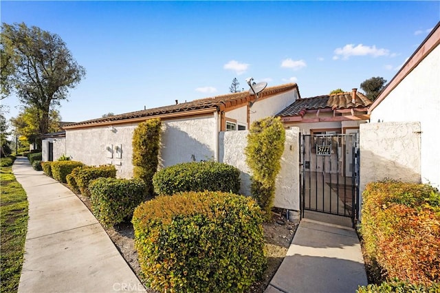 exterior space with a gate, fence, a tiled roof, and stucco siding