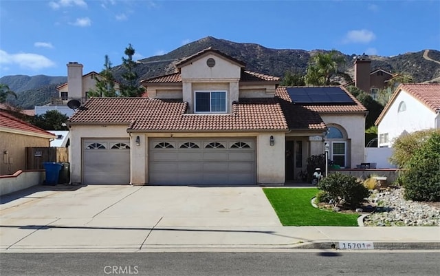 mediterranean / spanish home with a garage, a tile roof, a mountain view, and stucco siding