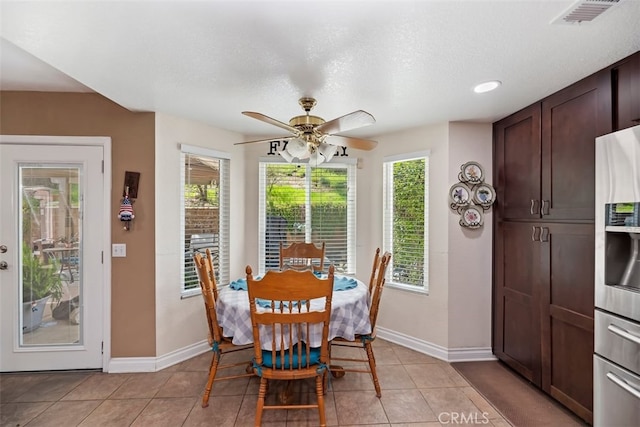 dining room featuring baseboards, a ceiling fan, visible vents, and light tile patterned floors