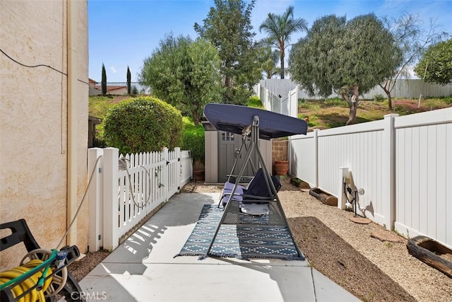 view of patio / terrace with a fenced backyard, an outdoor structure, and a shed