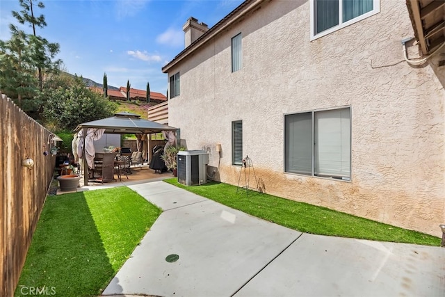 back of house featuring central AC unit, a chimney, a gazebo, stucco siding, and a patio area