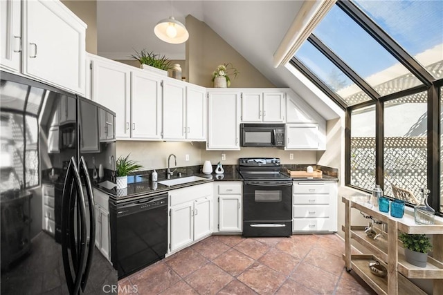 kitchen with vaulted ceiling with skylight, a sink, white cabinetry, black appliances, and dark countertops