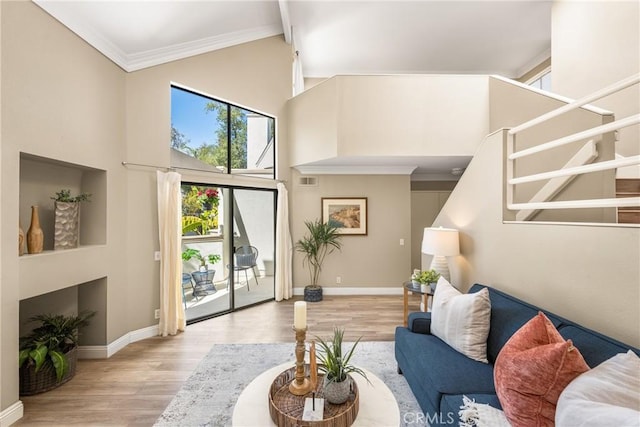 living area with ornamental molding, stairway, a towering ceiling, and baseboards