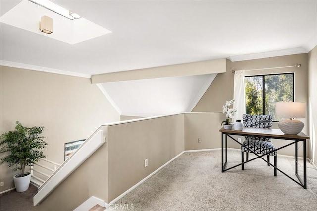 carpeted office featuring lofted ceiling with skylight, crown molding, and baseboards